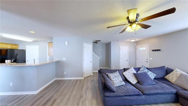 living room featuring ceiling fan, light hardwood / wood-style floors, and a textured ceiling