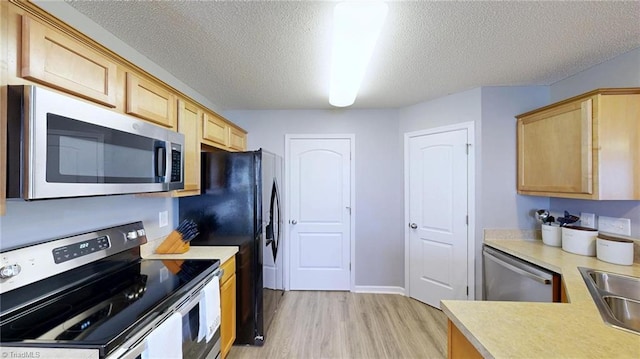 kitchen with light brown cabinetry, sink, a textured ceiling, light wood-type flooring, and appliances with stainless steel finishes