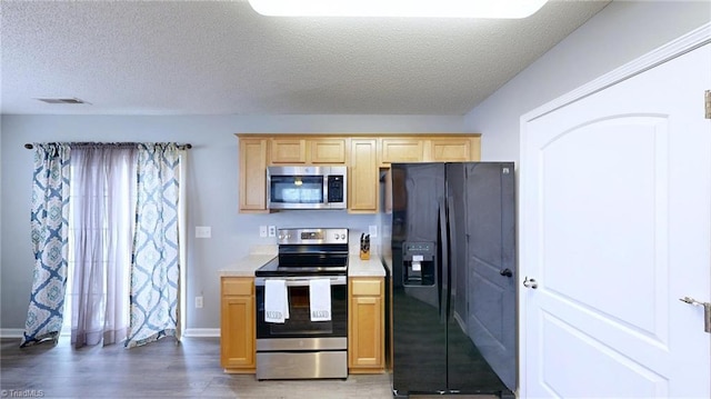 kitchen with light brown cabinetry, dark wood-type flooring, a textured ceiling, and appliances with stainless steel finishes