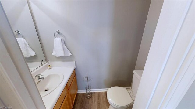 bathroom with hardwood / wood-style flooring, vanity, and toilet