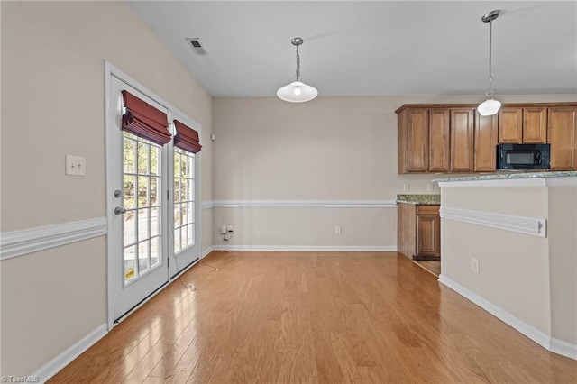 kitchen featuring decorative light fixtures, baseboards, light wood-style flooring, black microwave, and brown cabinets