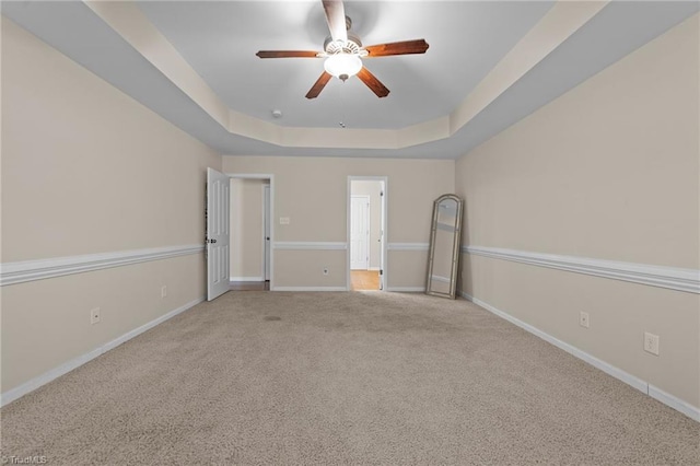 unfurnished bedroom featuring baseboards, a ceiling fan, carpet, and a raised ceiling