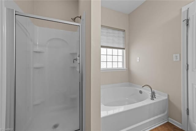 full bath featuring a stall shower, baseboards, and a garden tub