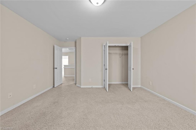 unfurnished bedroom featuring a closet, light carpet, and baseboards