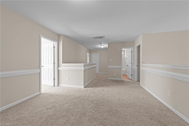spare room with baseboards, visible vents, and light carpet