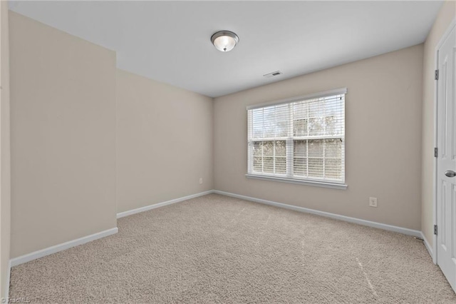 empty room with baseboards, visible vents, and carpet