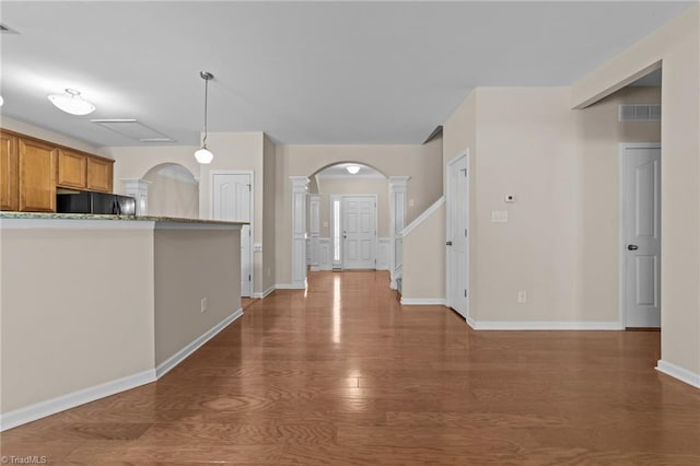 kitchen with wood finished floors, fridge, brown cabinets, visible vents, and arched walkways