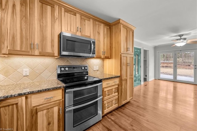 kitchen featuring dark stone countertops, ceiling fan, stainless steel appliances, light hardwood / wood-style floors, and decorative backsplash