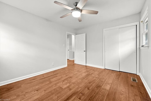 unfurnished bedroom featuring hardwood / wood-style floors, ceiling fan, and a closet