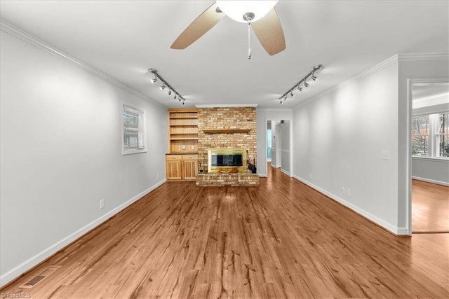 unfurnished living room with crown molding, wood-type flooring, and a brick fireplace