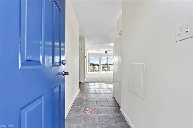hallway with tile patterned flooring, baseboards, and a textured ceiling