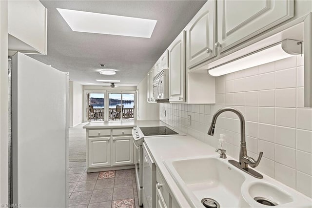 kitchen with white appliances, a sink, light countertops, a textured ceiling, and tasteful backsplash
