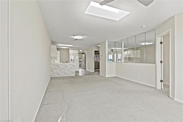 unfurnished living room with baseboards and carpet flooring