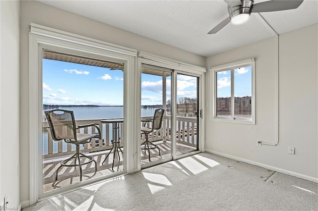 carpeted spare room with a textured ceiling, a ceiling fan, baseboards, and a water view
