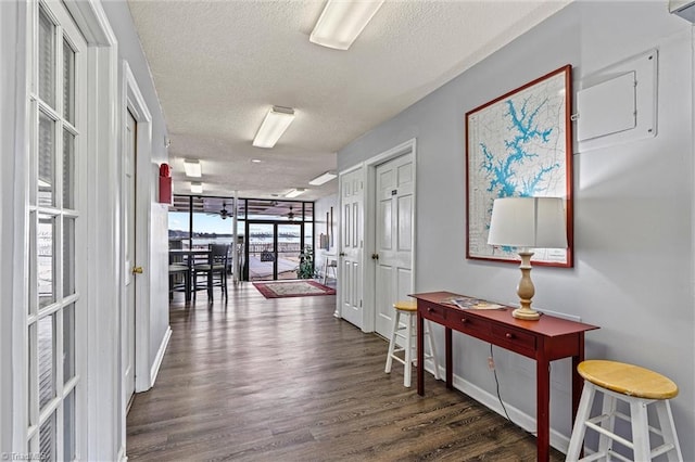 hall with a textured ceiling, baseboards, and wood finished floors
