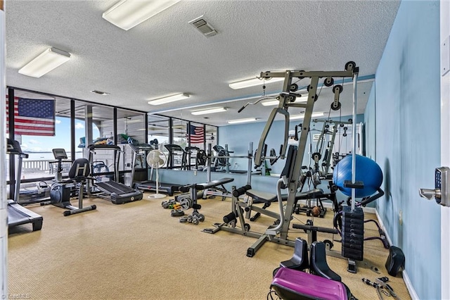gym with a wall of windows, baseboards, visible vents, and a textured ceiling