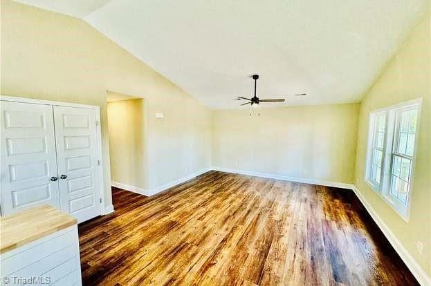 spare room with vaulted ceiling, ceiling fan, wood finished floors, and baseboards