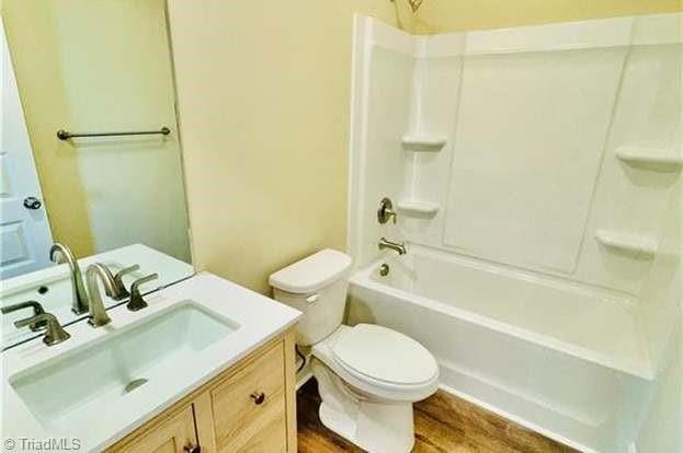 full bath featuring wood finished floors, vanity, toilet, and bathing tub / shower combination