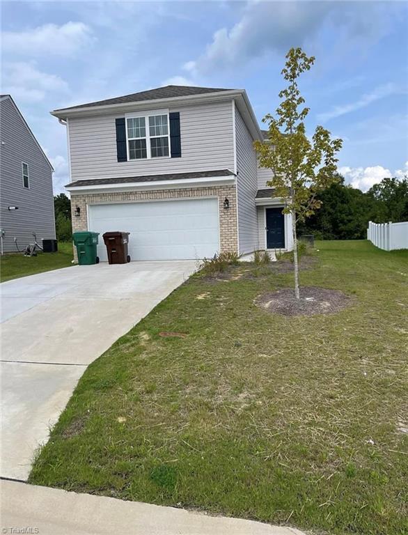 view of front of home with a garage, central AC, and a front yard