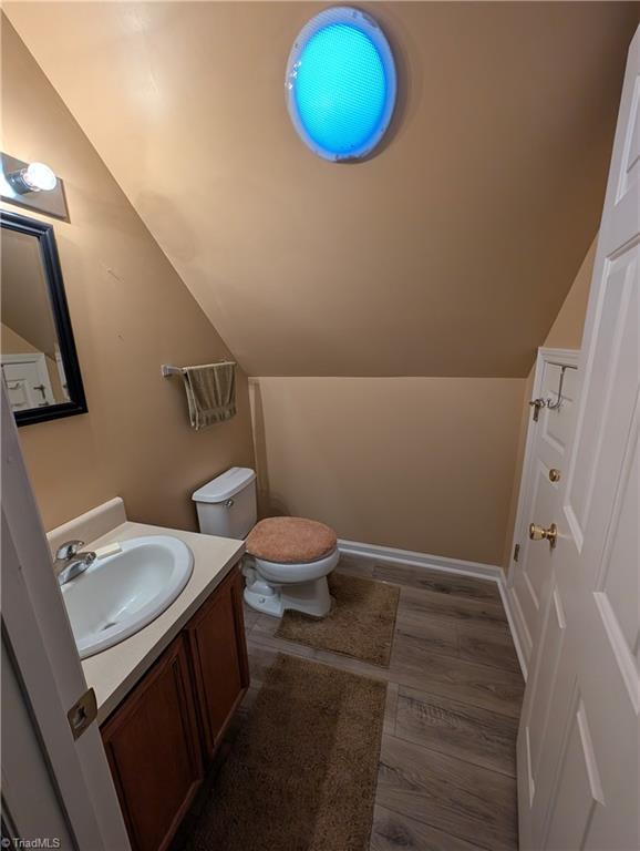 bathroom featuring vanity, vaulted ceiling, toilet, and hardwood / wood-style floors