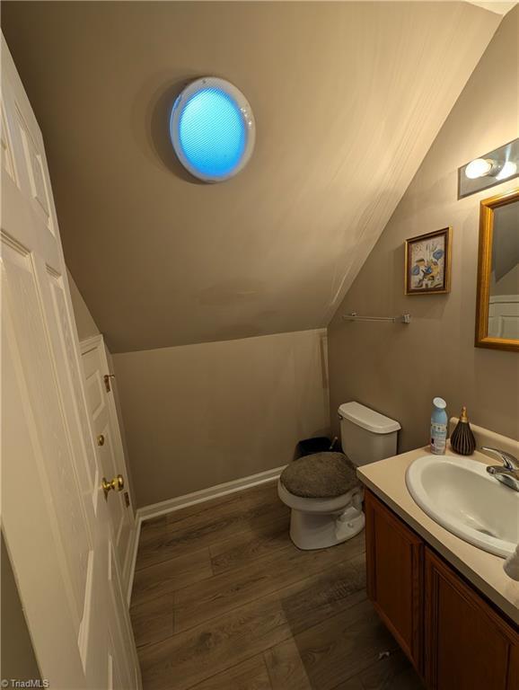 bathroom featuring lofted ceiling, wood-type flooring, vanity, and toilet