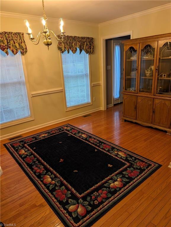 dining area with ornamental molding, hardwood / wood-style floors, and a chandelier