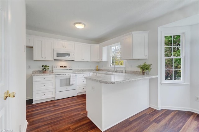 kitchen with white cabinetry, white appliances, dark hardwood / wood-style floors, and kitchen peninsula