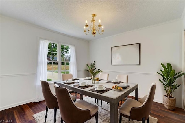 dining room featuring dark wood-type flooring, a chandelier, a textured ceiling, and ornamental molding