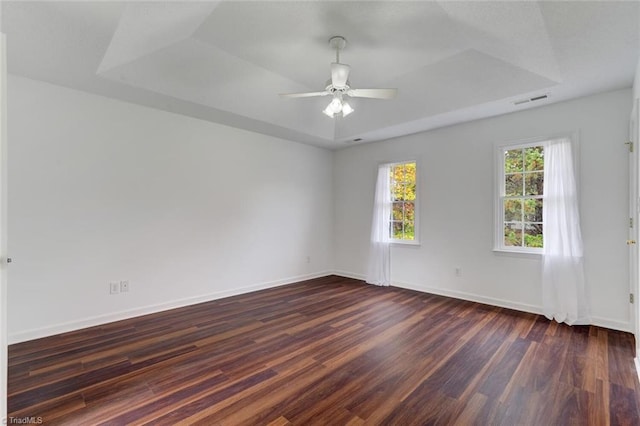 unfurnished room with dark hardwood / wood-style floors, ceiling fan, and a tray ceiling