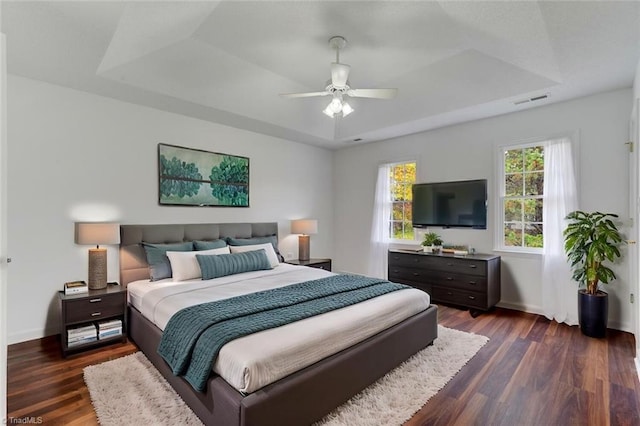 bedroom featuring a raised ceiling, ceiling fan, and dark hardwood / wood-style floors