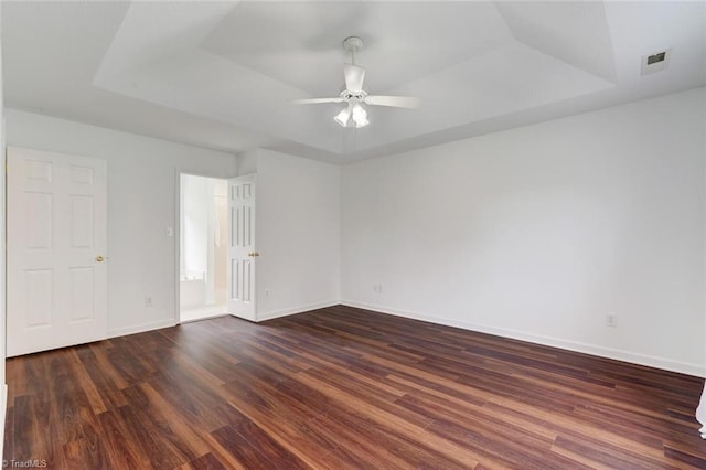 empty room featuring dark wood-type flooring, ceiling fan, and a raised ceiling