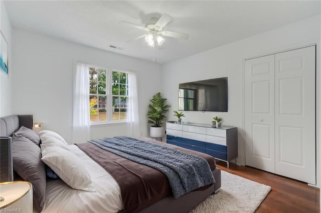 bedroom featuring dark wood-type flooring, a closet, and ceiling fan