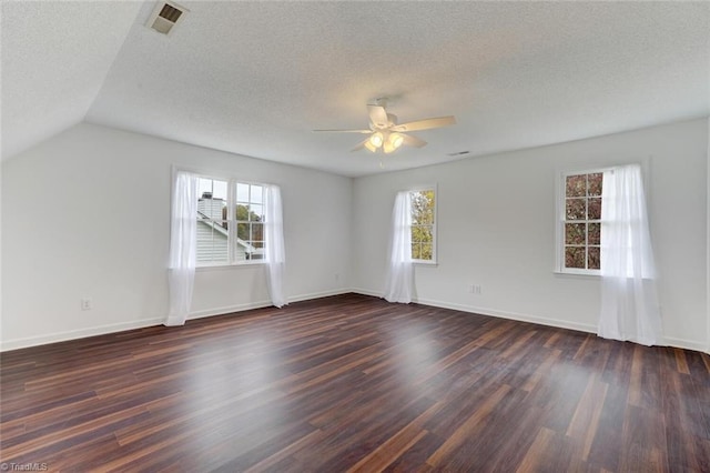 empty room featuring a textured ceiling, lofted ceiling, dark hardwood / wood-style floors, and ceiling fan