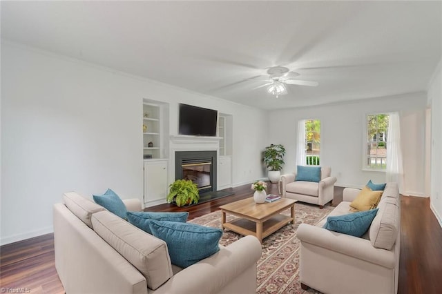 living room with built in features, wood-type flooring, and ceiling fan