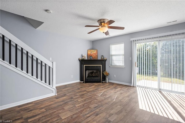 unfurnished living room with dark wood-type flooring, a textured ceiling, and ceiling fan