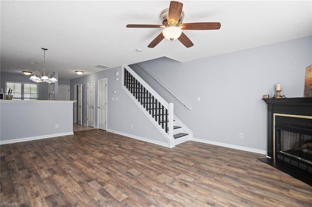 unfurnished living room featuring ceiling fan with notable chandelier and dark wood-type flooring