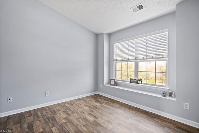 empty room with hardwood / wood-style floors and a textured ceiling