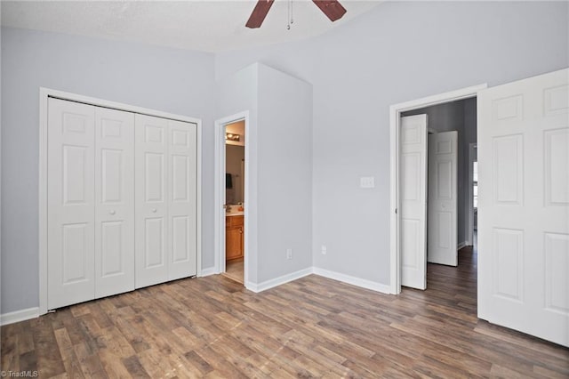 unfurnished bedroom with a closet, ceiling fan, dark hardwood / wood-style floors, and connected bathroom