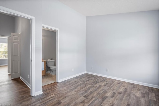 unfurnished bedroom featuring dark hardwood / wood-style floors and ensuite bath