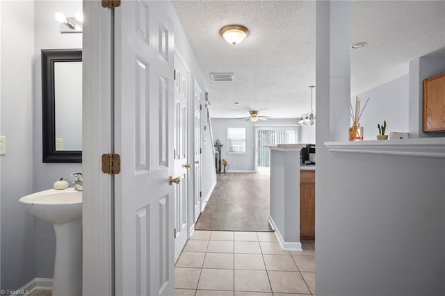 hall featuring a textured ceiling and light tile patterned floors