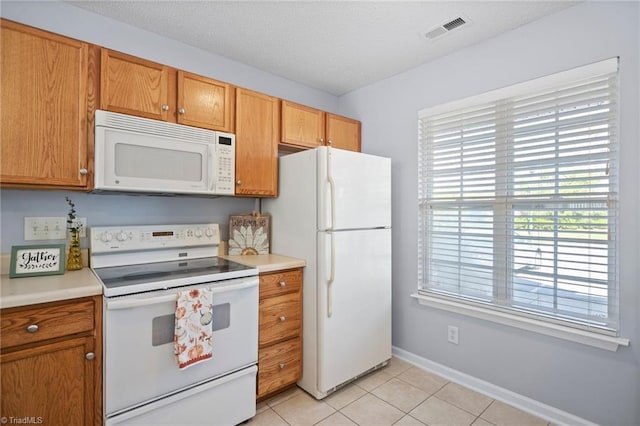 kitchen with white appliances, a textured ceiling, and light tile patterned flooring