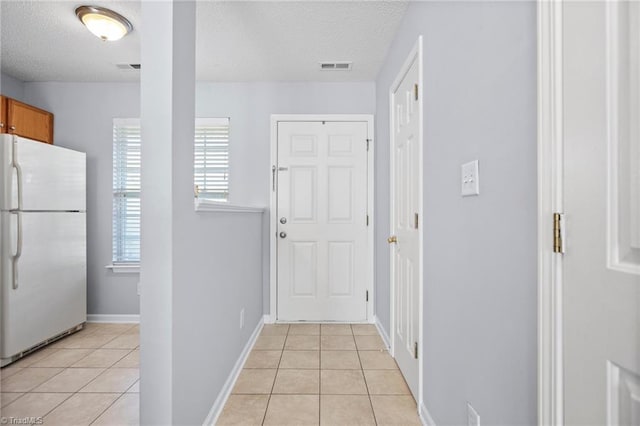 corridor featuring a textured ceiling and light tile patterned floors