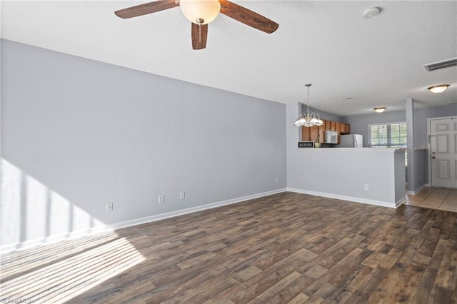 unfurnished living room with dark wood-type flooring and ceiling fan with notable chandelier