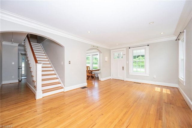 interior space with ornamental molding, a wealth of natural light, and light wood-type flooring