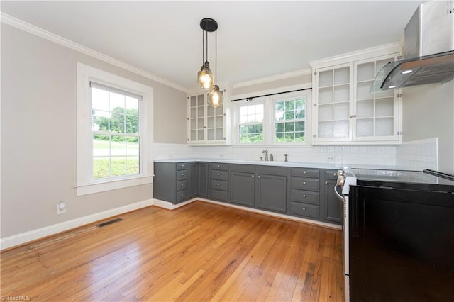 kitchen with gray cabinetry, electric range oven, pendant lighting, range hood, and decorative backsplash