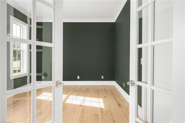 empty room with crown molding, wood-type flooring, and french doors