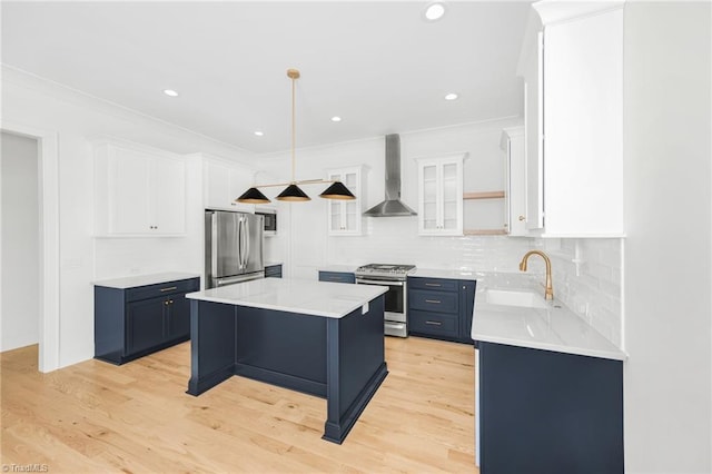 kitchen featuring white cabinetry, a kitchen bar, a center island, stainless steel appliances, and wall chimney range hood