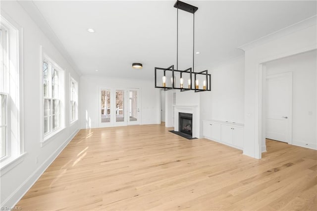 unfurnished living room featuring ornamental molding, an inviting chandelier, and light wood-type flooring