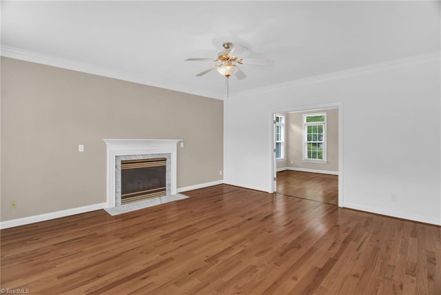 unfurnished living room featuring crown molding, ceiling fan, baseboards, wood finished floors, and a fireplace