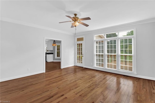 empty room featuring crown molding, ceiling fan, hardwood / wood-style flooring, and baseboards